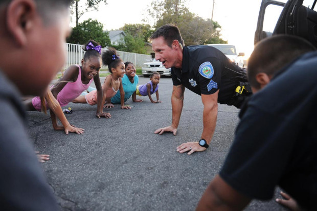 police officer doing push ups with children