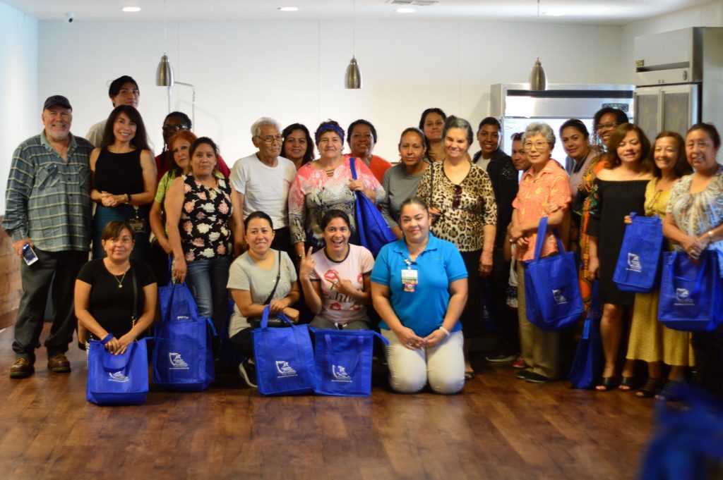 A group of people posing for a picture while holding blue bags containg information from Community Vital Signs.